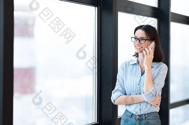 微笑的女孩在窗户旁用智能手机聊天