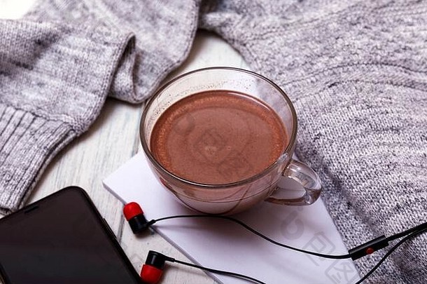 一杯热咖啡或热巧克力，带耳机，放在质朴的木桌上，特写照片，带马克杯的保暖毛衣，冬季早晨概念，俯视图