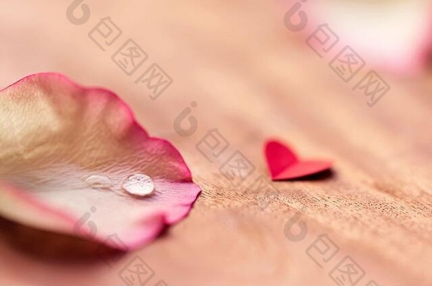 在木制桌子上，粉红色玫瑰花瓣上有一颗可爱的<strong>小</strong>红心，上面有一个美丽的<strong>小水滴</strong>，为情人节、婚礼、周年纪念留有空间。概念