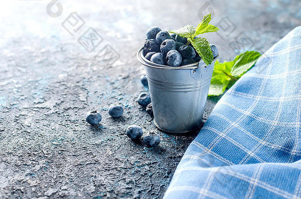 成熟的蓝莓迷你桶叶子薄荷黑暗混凝土背景
