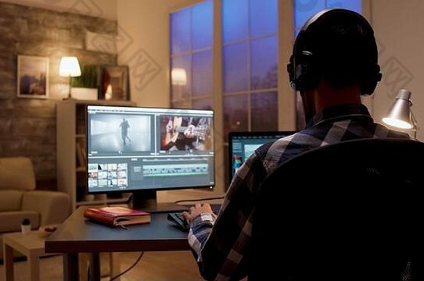 内容创建者夜间在家庭办公室工作的后视图。家庭办公室的视频编辑器。