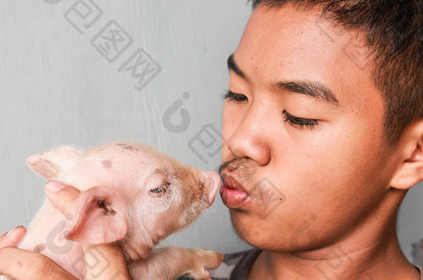 年轻的亚洲男孩亲吻他的宠物小猪。宠物概念。