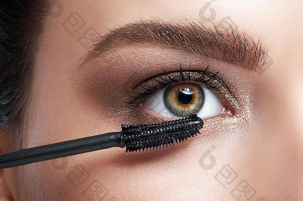 特写镜头美丽的年轻的女人应用睫毛膏眼睛睫毛化妆品刷
