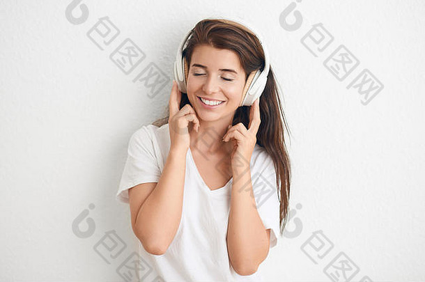 有吸引力的年轻的女人关闭眼睛听音乐<strong>立体</strong>声耳机活泼的<strong>微</strong>笑白色墙复制水疗中心