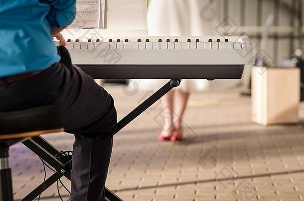 特写镜头：<strong>单身</strong>艺人在婚礼<strong>派对</strong>上弹奏键盘，背景是新娘跳舞