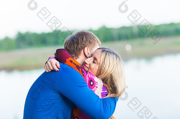 美丽的年轻情侣在湖边拥抱的肖像。