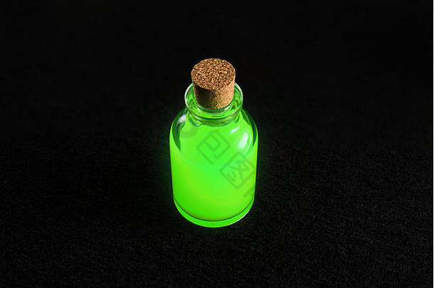 透明的瓶子，充满活力的绿色液体。在黑暗的背景下孤立。