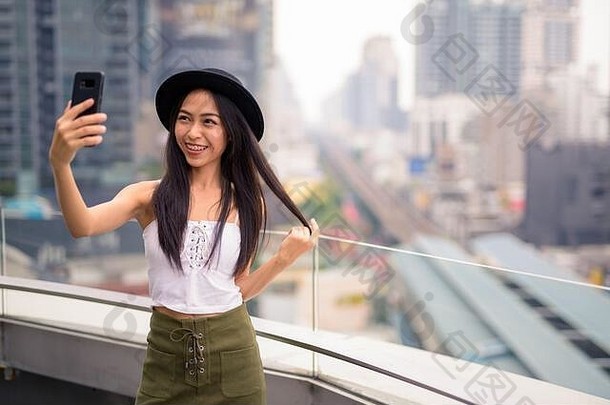 快乐年轻的美丽的亚洲旅游女人采取自拍视图城市