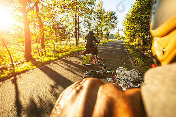 在阳光明媚的早晨骑摩托车的摩托车手