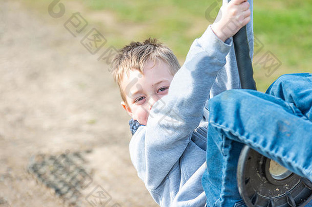 一个患有多动症、自闭症、阿斯伯格综合症的英俊小男孩在夏日的阳光下快乐地荡秋千