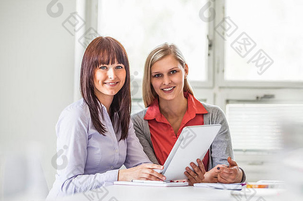 年轻女商人在办公室使用数字平板电脑的照片