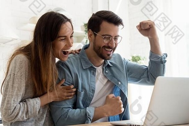 这对激动的夫妇在笔记本电脑上在线阅读好消息时感到欣喜若狂