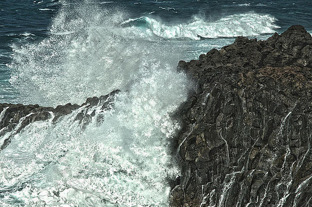 浪花飞溅在岩石熔岩海岸上