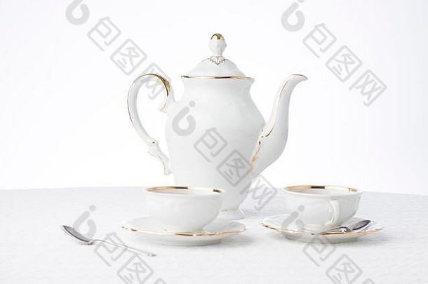 白色和<strong>金色</strong>的古董茶壶，在白色桌布上点缀着鲜花和<strong>质感</strong>，为文本提供了空间