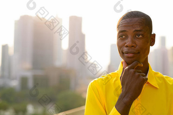 年轻的非洲秃头商人在城市的视野中思考和仰望