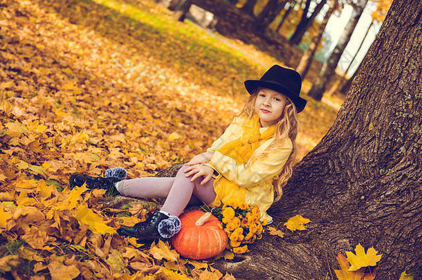 美丽的金发小女孩，秋日背景下长着大南瓜