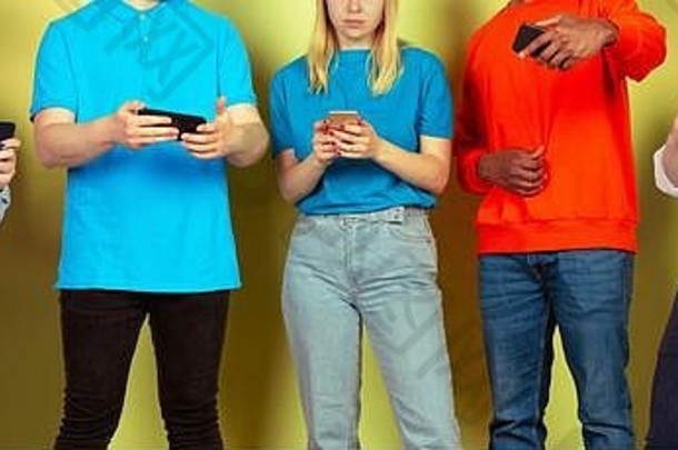 一群使用移动智能手机的朋友。青少年对新技术趋势上瘾。闭合。千禧年的人们发短信、滚动、聊天、看视频或在线购物。与设备连接。