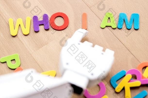 机器人手臂用手指指着五颜六色的字母，组成了“我是谁”的句子