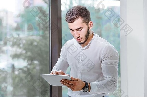阿拉伯裔年轻男子在室内使用平板电脑的特写镜头