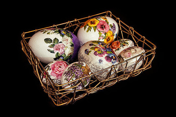 五颜六色的复活节彩蛋堆在金色的铁丝筐里。复活节假期。深色背景。<strong>春天</strong>的象征。