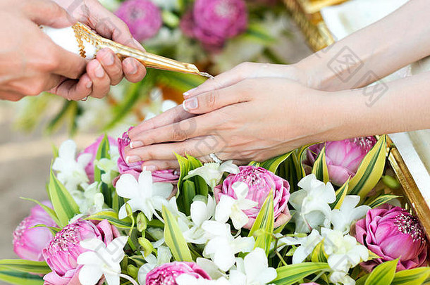 泰国婚礼浇水仪式，在泰国文化婚礼仪式中，新娘的手从长辈那里接受圣水
