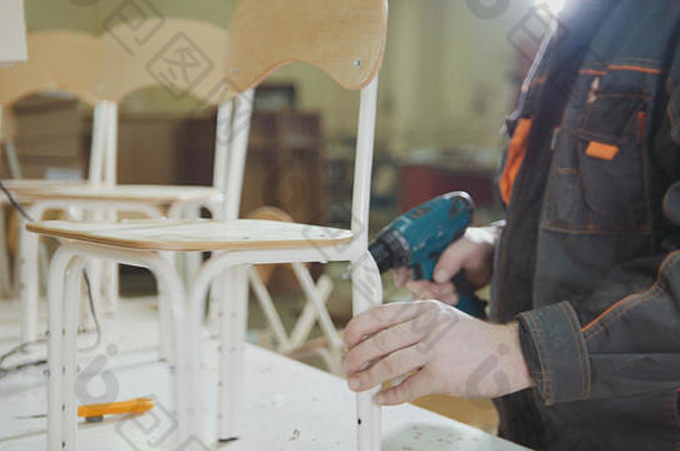 工人木匠正在一家家具厂为孩子们拧椅子