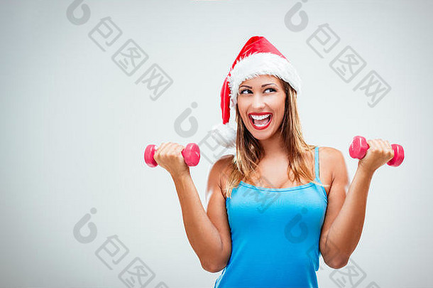 戴着圣诞老人的帽子，举着哑铃，面带微笑的快乐健身女士，<strong>欢快</strong>、清新、充满<strong>活力</strong>。白色背景。