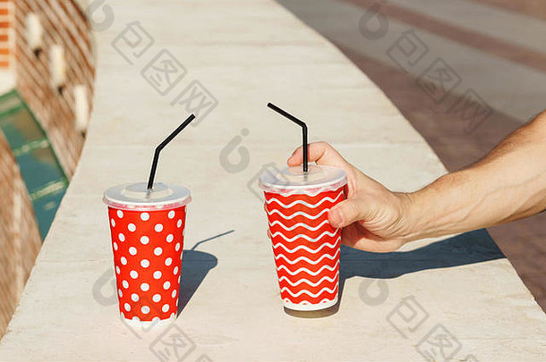 两个带吸管外卖饮料的纸杯。纸杯<strong>夏日柠檬水</strong>。特写。男人的手拿着纸杯
