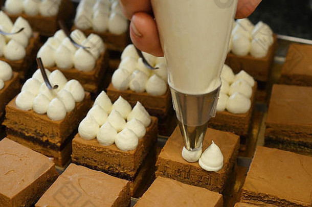 奶油被挤在巧克力蛋糕上。把奶油挤在蛋糕上