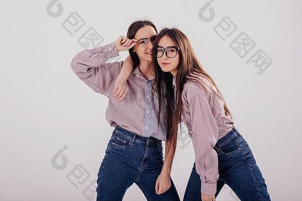 快乐的大气姐妹双胞胎站摆姿势工作室白色背景