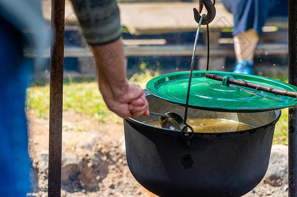 在篝火上用锅烹调食物。夏令营的概念。