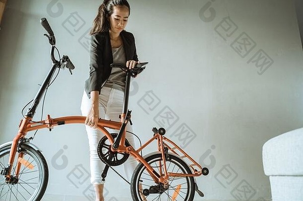 亚洲年轻的女人站生活房间开放褶皱<strong>折叠自行车</strong>