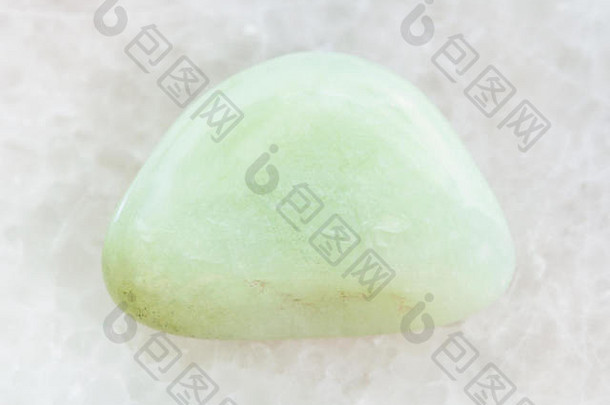 天然矿物岩石样品的宏观拍摄-在白色大理石背景上抛光的硬硅石（绿色石英）宝石
