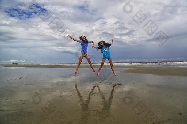 浅黑肤色的女人女孩持有手跳空气多云的一天海滩kiawah岛南卡罗莱纳穿洗澡西装