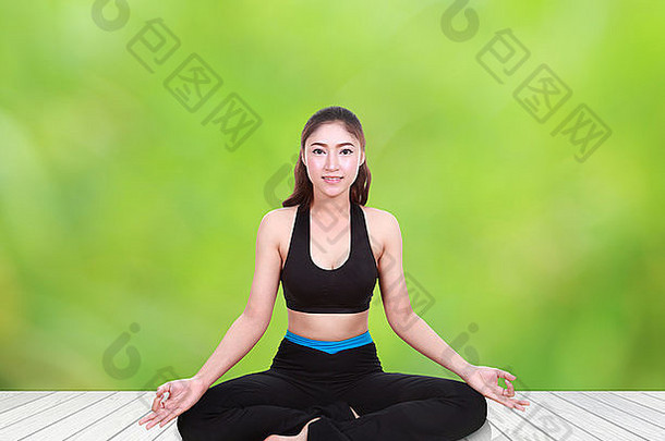年轻的女人瑜伽锻炼木地板上自然模糊背景