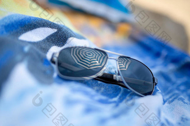 沙滩浴巾上的太阳镜通过沙滩伞反射阳光