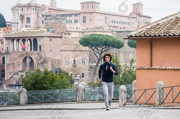 英俊的年轻的运动员慢跑罗马城市