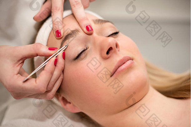 美容院美容师用镊子拔眉毛。