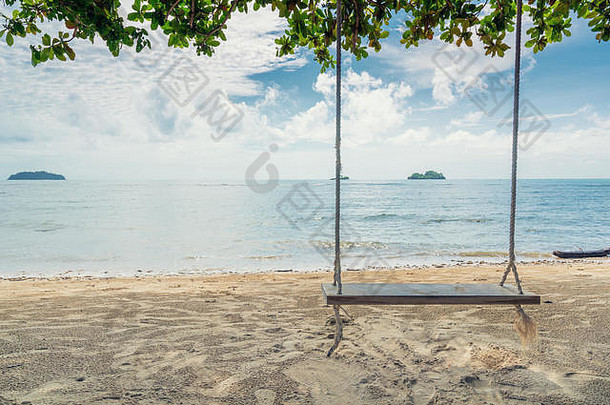 泰国普吉岛海滩附近的树上悬挂着木制秋千椅。暑期旅游与度假理念。