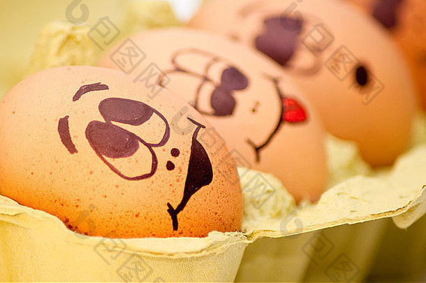 一组新鲜的鸡蛋，画着各种各样的表情，排列在一个鸡蛋纸盒里，与白色相对。