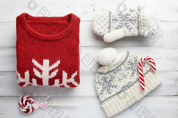 寒假针织毛衣、连指手套、帽子和白色木质背景的圣诞棒棒糖