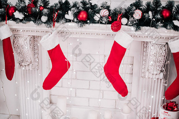 一张装饰精美的鲜红色圣诞袜挂在壁炉上等待礼物的近景照片。