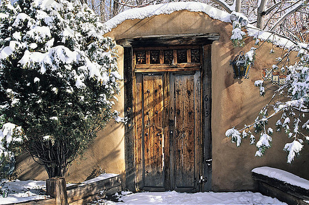 一扇镶在土坯墙上的木门，当被冬天的积雪覆盖时，似乎呈现出一种浪漫的气息。
