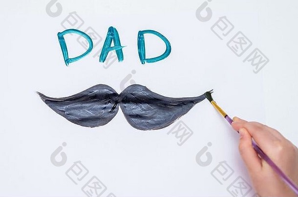 孩子的手在白纸上画着黑胡子，上面写着“爸爸”。父亲节和家庭观念。