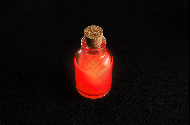 透明的瓶充满活力的红色的液体孤立的黑暗背景