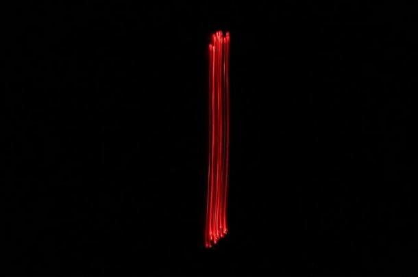 灯光画一张数字的照片，由仙女用红色鲜艳的霓虹灯在黑色背景下绘制。长曝光摄影。