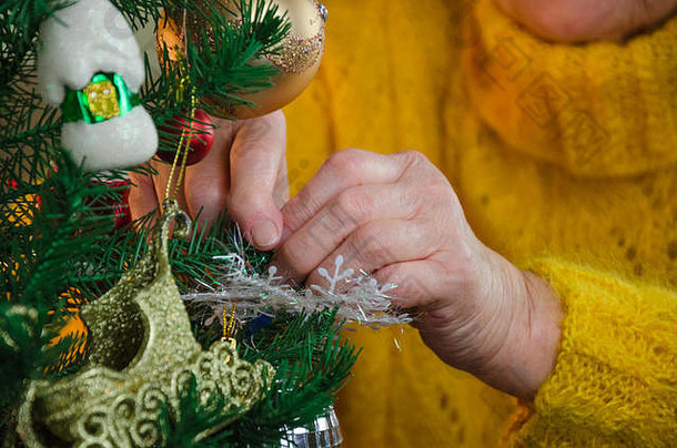 特写镜头祖母的手装修仙女演讲圣诞节树高级夫人把球玩具装饰冷杉分支奶奶黄色的针织滑轮