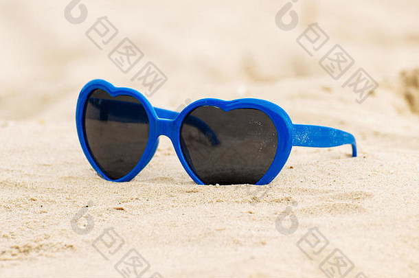 蓝色搞笑太阳镜，心形，躺在沙滩上，假期和夏天，保护眼睛