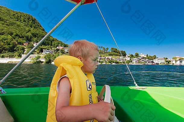 小男孩在阿尔卑斯湖上驾驶水上小船。