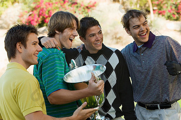 四名年轻的高尔夫球手拿着奖杯摆姿势